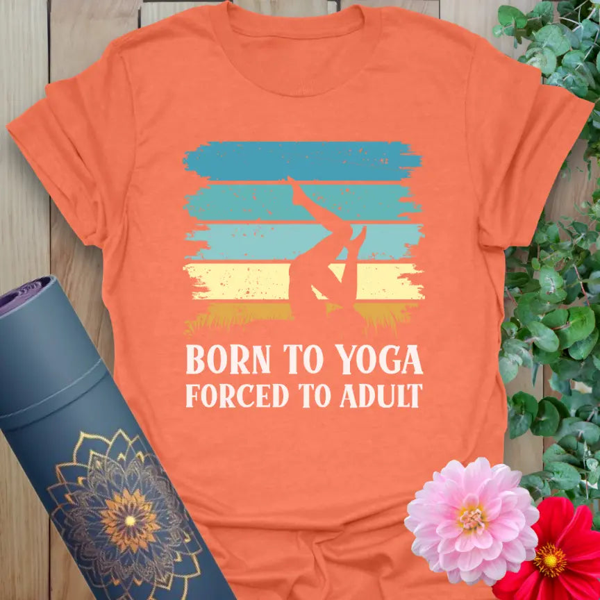 Flatlay of heather orange Adult T-Shirt featuring bold “Born to Yoga, Forced to Adult” graphic, retro yoga humor.