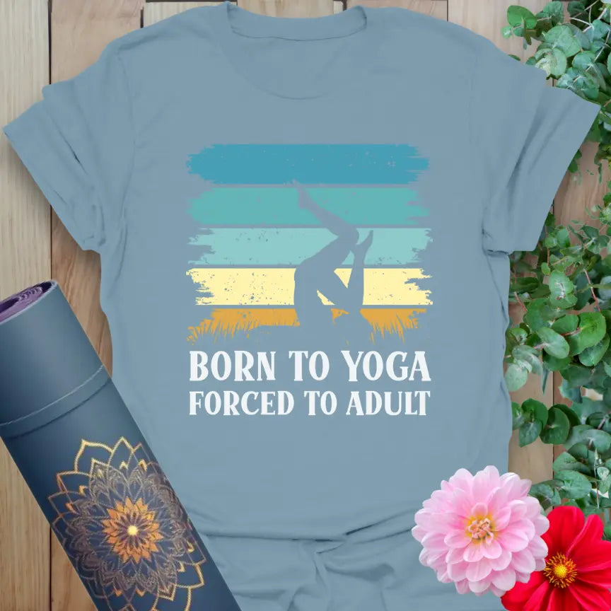 Flatlay of Sone Blue Adult T-Shirt featuring spiritual-meets-humor “Born to Yoga, Forced to Adult” design.