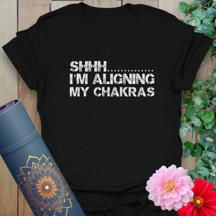Classic black cotton yoga t-shirt showcasing "Shhh... Aligning Chakras" humor for conscious, heart-centered living.