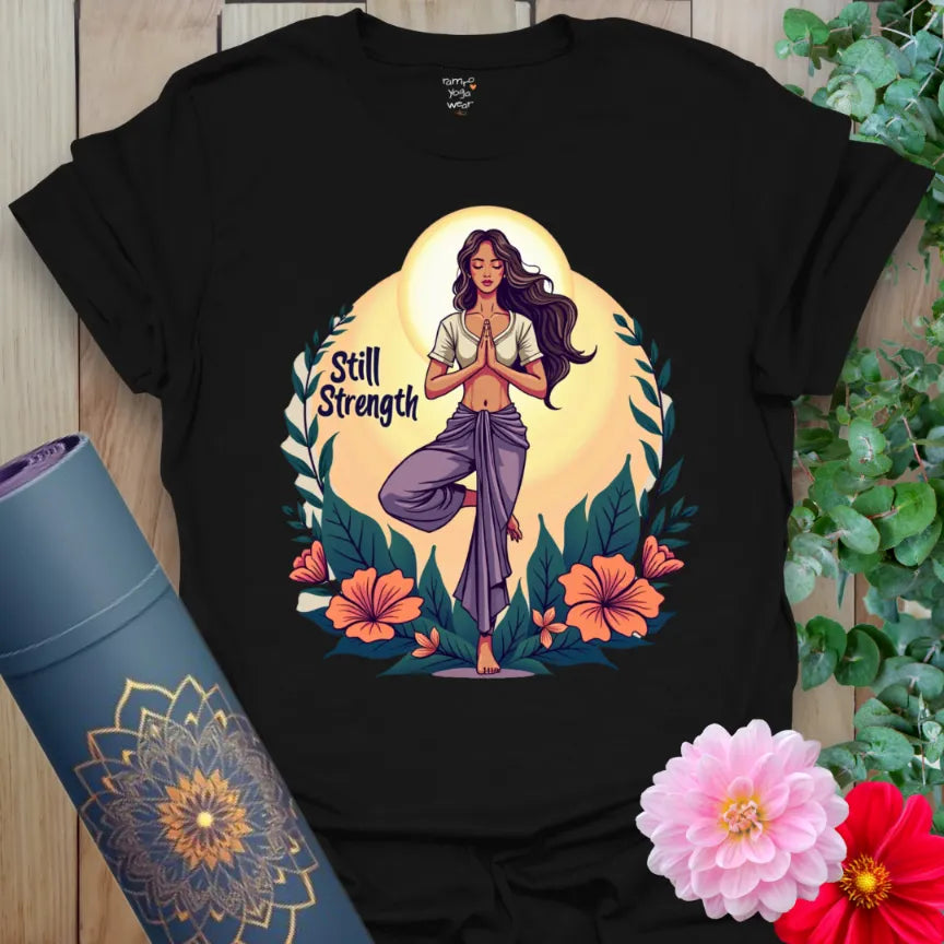 Classic black cotton tee showcasing vibrant yogi in Tree Pose surrounded by florals and “Still Strength” message, perfect for empowered lifestyle wear.