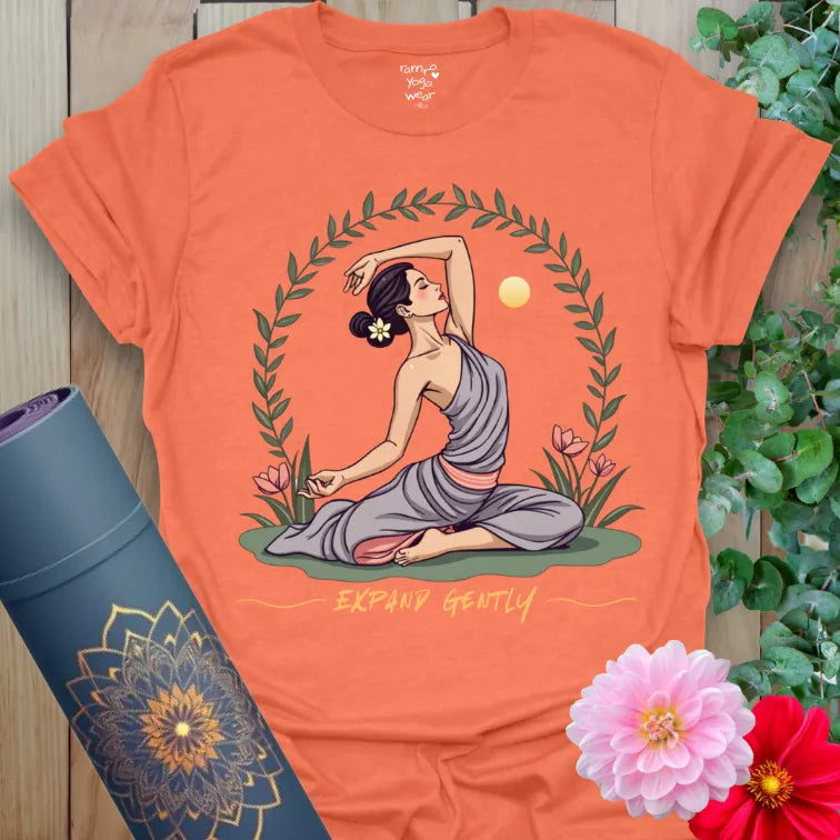 Vibrant orange yoga t-shirt showcasing heart-opening yogi pose surrounded by flowers and rising sun.