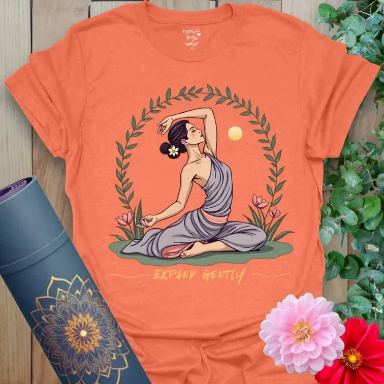 Vibrant orange yoga t-shirt showcasing heart-opening yogi pose surrounded by flowers and rising sun.