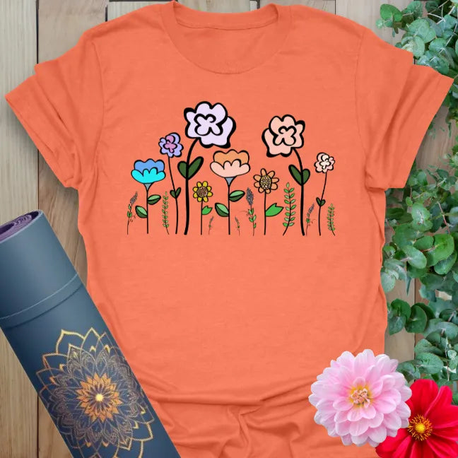 Vibrant orange yoga t-shirt showcasing playful multicolored wildflowers for nature-connected, soulful living.