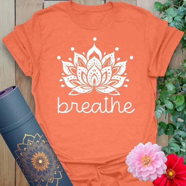 Vibrant orange yoga t-shirt showcasing detailed lotus and "breathe" design inspiring calm, soulful presence.