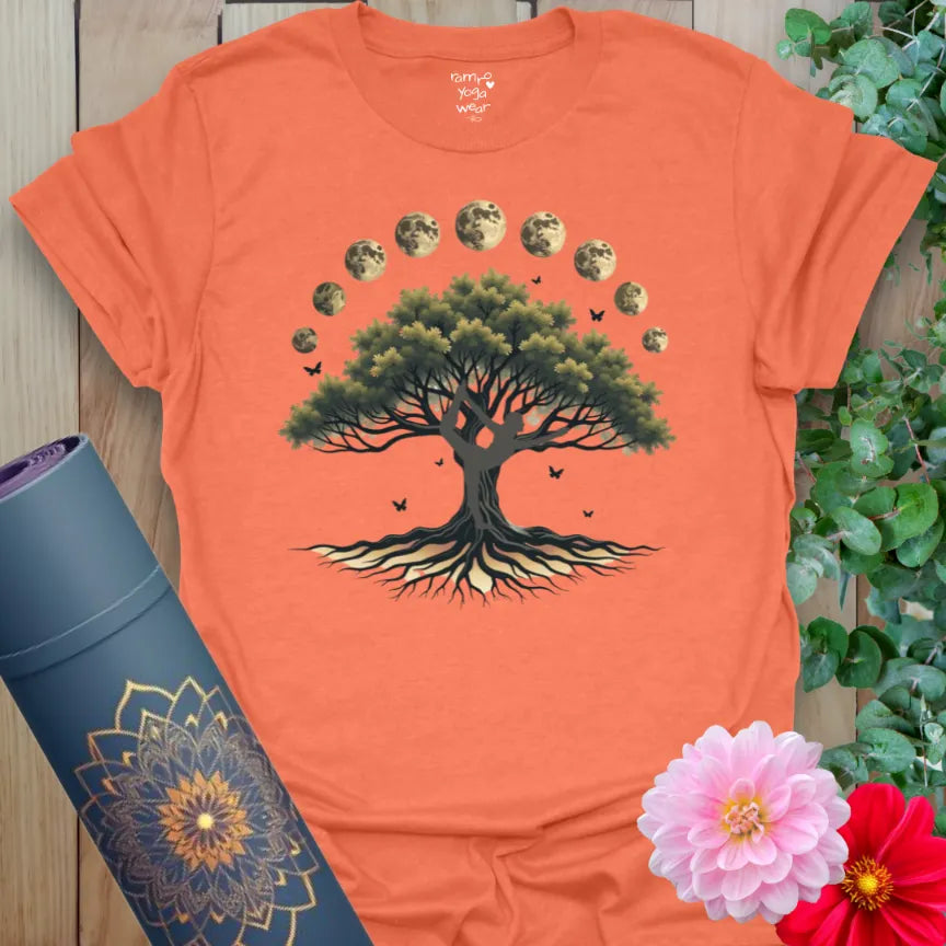 Vibrant orange yoga t-shirt showcasing sacred tree under moon phases for mindful movement and soulful transformation.