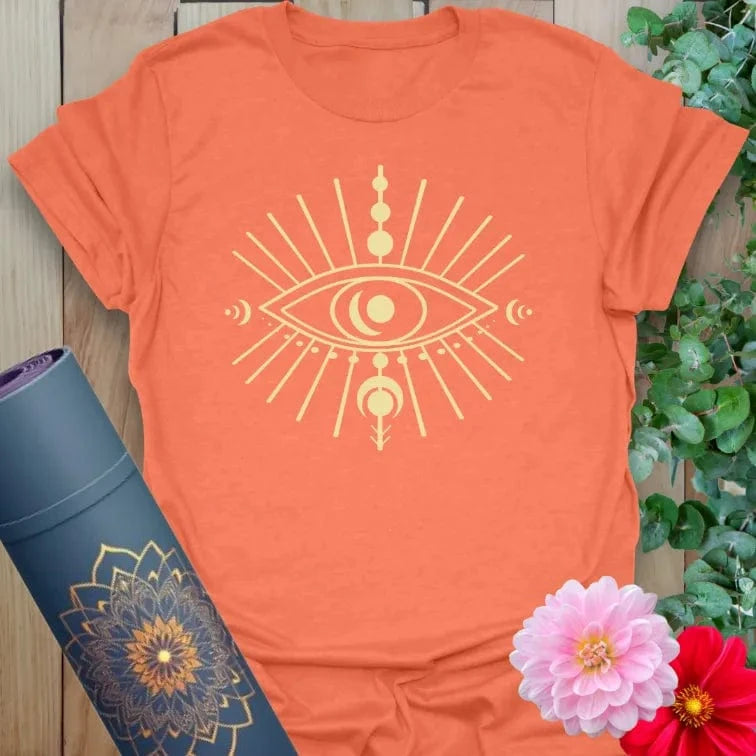 Vibrant orange yoga t-shirt showcasing mystical eye artwork with lunar phases symbolizing intuition and conscious growth.