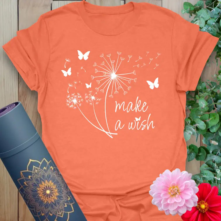 Vibrant orange yoga t-shirt showcasing dreamy dandelion and butterfly artwork with "Make a Wish" quote for soulful living.