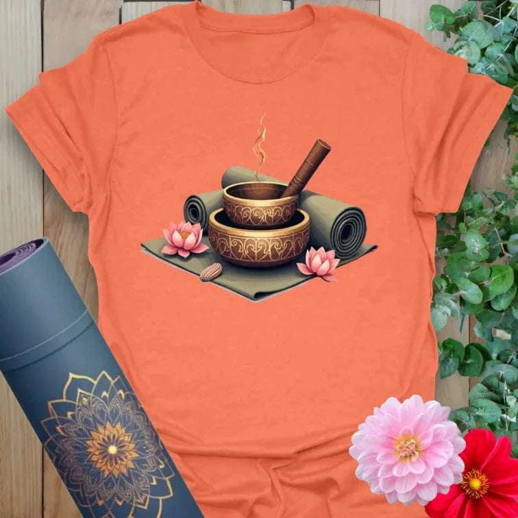 Vibrant orange yoga t-shirt showcasing meditation bowls, incense, and lotus artwork inspiring conscious calm and spiritual living.