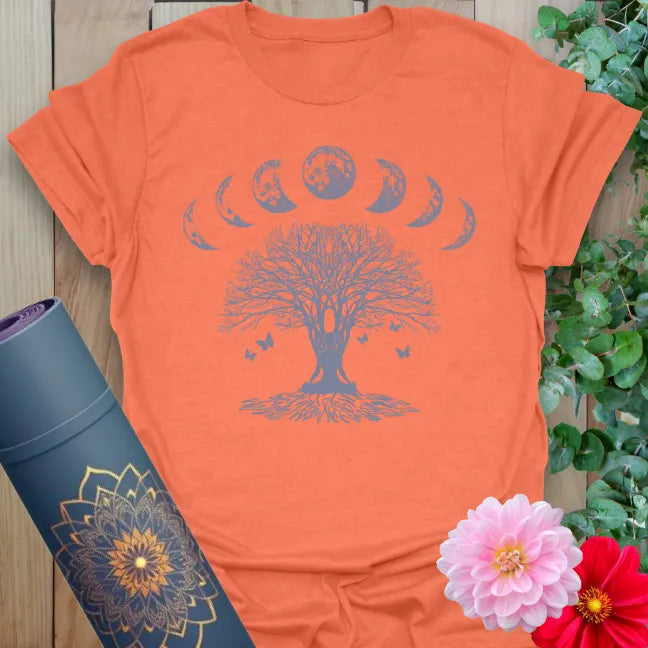 Vibrant orange yoga t-shirt showcasing sacred tree artwork with lunar cycle and butterfly design inspiring mindful living and transformation.