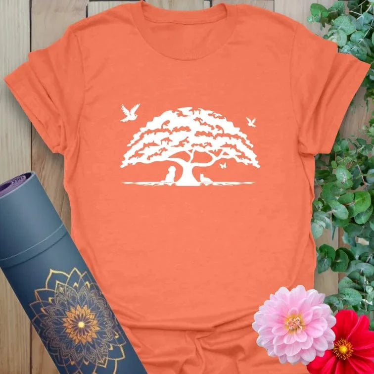 Vibrant orange yoga t-shirt showcasing ancient oak tree and bird design inspiring resilience, mindful living, and nature connection.