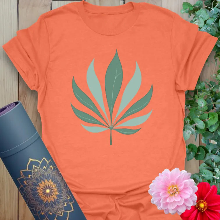 Vibrant orange yoga t-shirt showcasing stylized palm leaf artwork for grounded, soulful, earth-connected living.