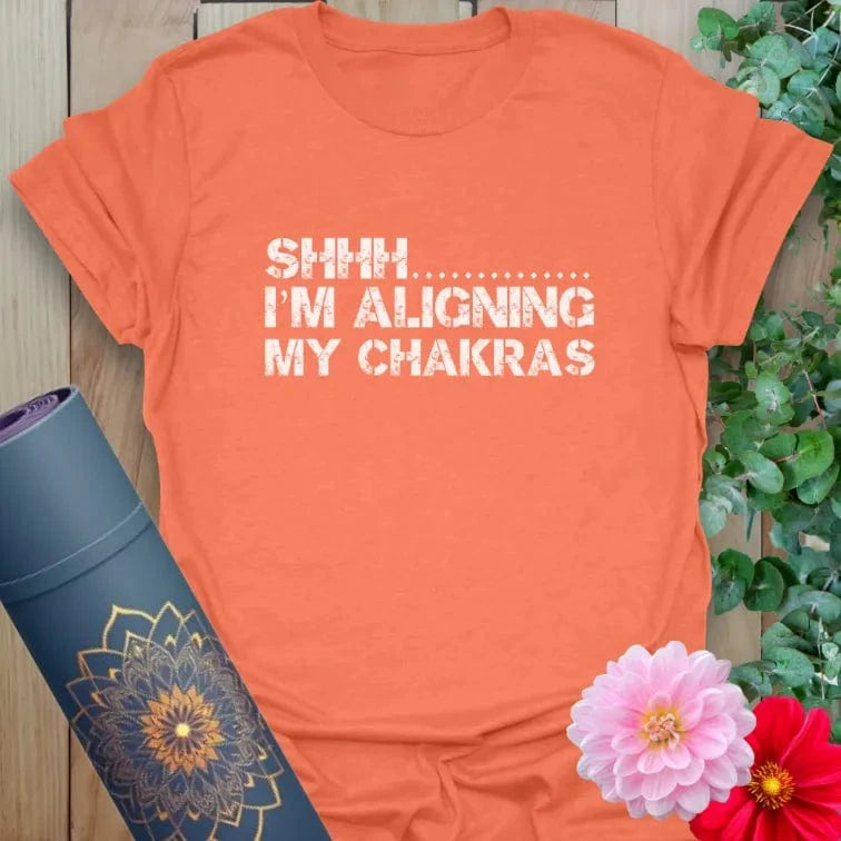 Vibrant orange yoga t-shirt showcasing funny chakra alignment message inspiring peaceful, conscious movement.