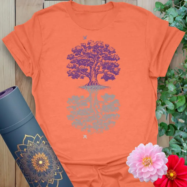Vibrant orange yoga t-shirt showcasing intricate tree of life design inspiring conscious, heart-centered living.