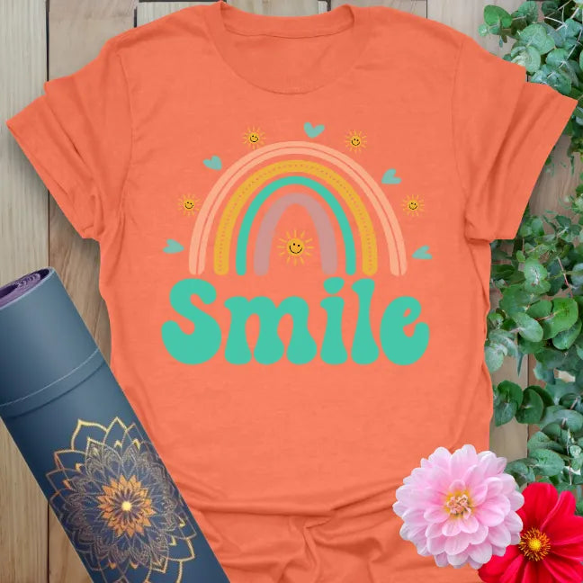 Vibrant orange yoga t-shirt showcasing cheerful rainbow and playful "Smile" design promoting positivity and mindful happiness.