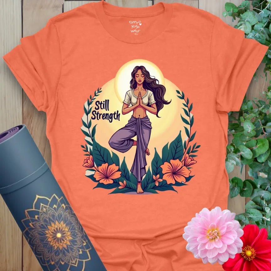Vibrant orange t-shirt with divine feminine design, floral elements, and inspiring “Still Strength” quote for empowered yoga wear.