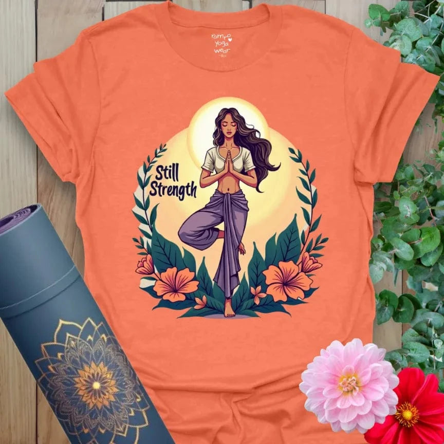 Vibrant orange t-shirt with divine feminine design, floral elements, and inspiring “Still Strength” quote for empowered yoga wear.