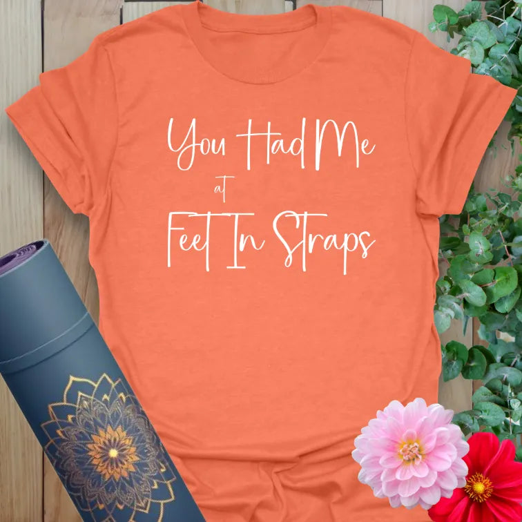 Vibrant orange tee with humorous “Feet in Straps” quote for reformer pilates fans and mindful movers.
