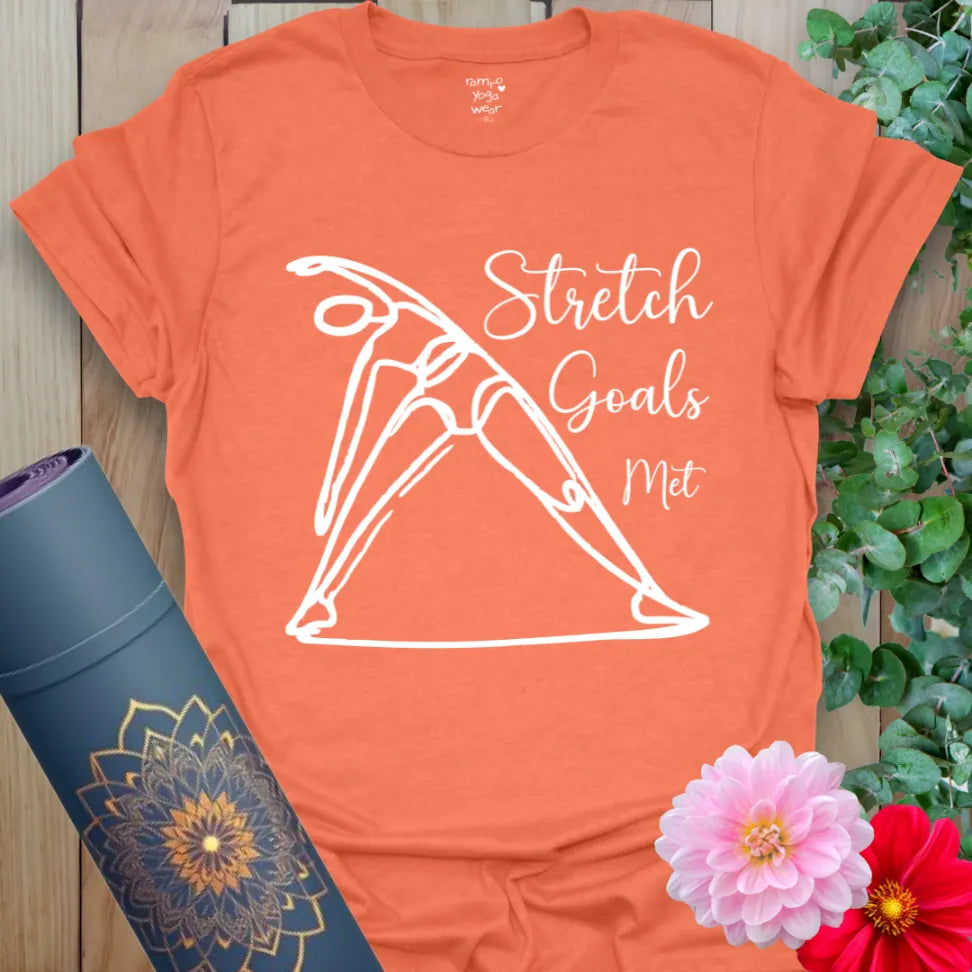 Vibrant orange t-shirt with dynamic stretch pose and playful “Stretch Goals Met” script for yoga practice and lifestyle wear.