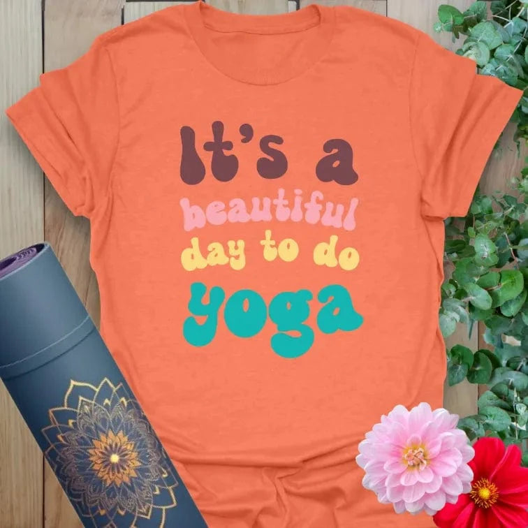 Vibrant orange t-shirt with colorful motivational yoga quote for playful, conscious movement lovers.