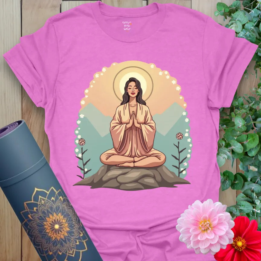 Radiant orchid-colored yoga tee with serene meditator artwork framed by mountains and soft halo glow.