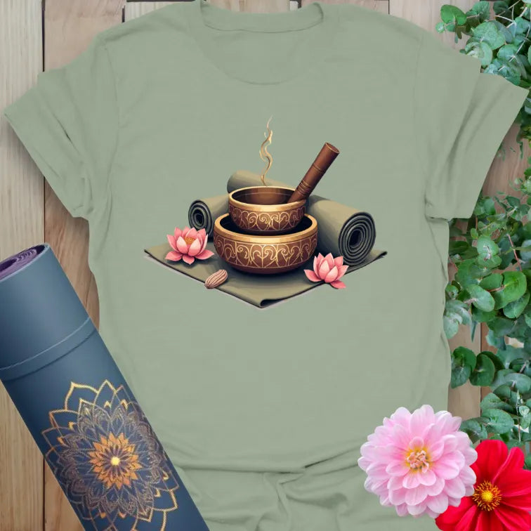 Calm sage green yoga t-shirt featuring detailed mindfulness altar with singing bowls, yoga mats, and incense for soulful, conscious living.