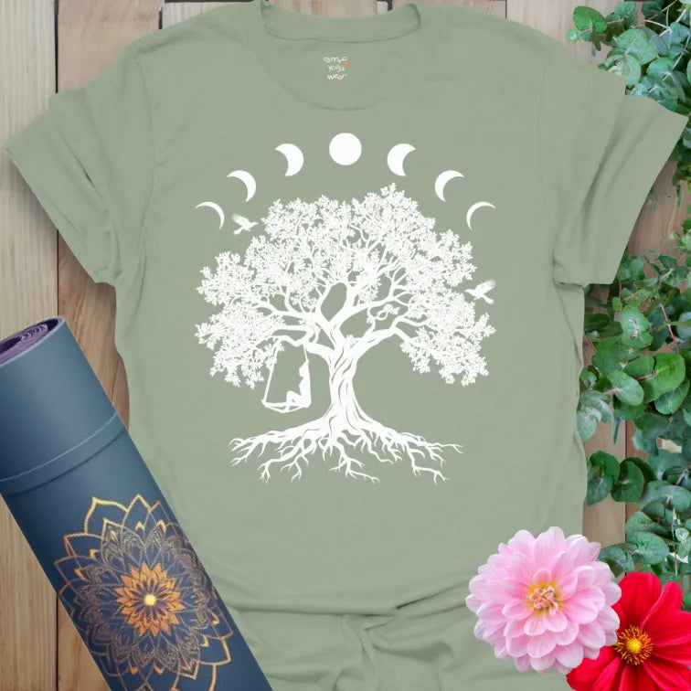 Calm sage green yoga t-shirt featuring sacred tree of life crowned by lunar phases with swinging figure inspiring soulful, heart-centered presence.