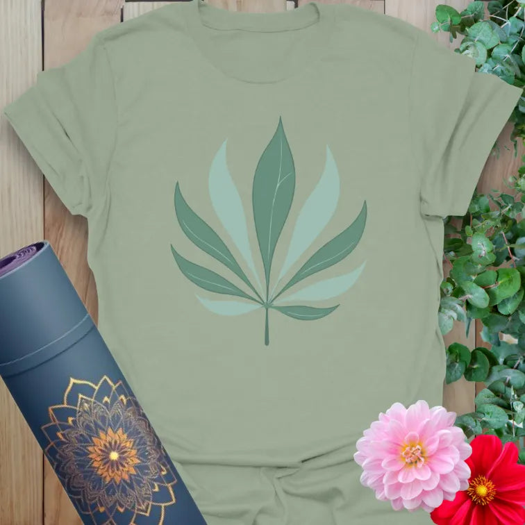 Calm sage green yoga t-shirt featuring soft palm leaf illustration representing balance, peace, and conscious movement.