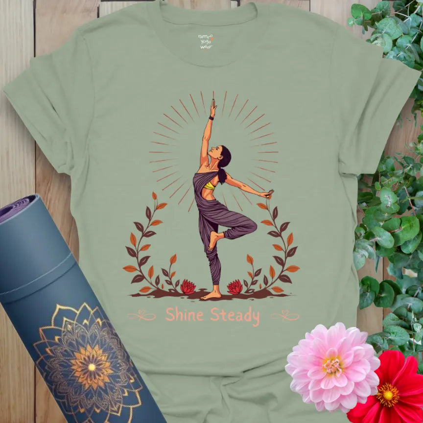 Calm sage green yoga t-shirt featuring graceful tree pose yogi illustration with “Shine Steady” message for grounded, peaceful energy.