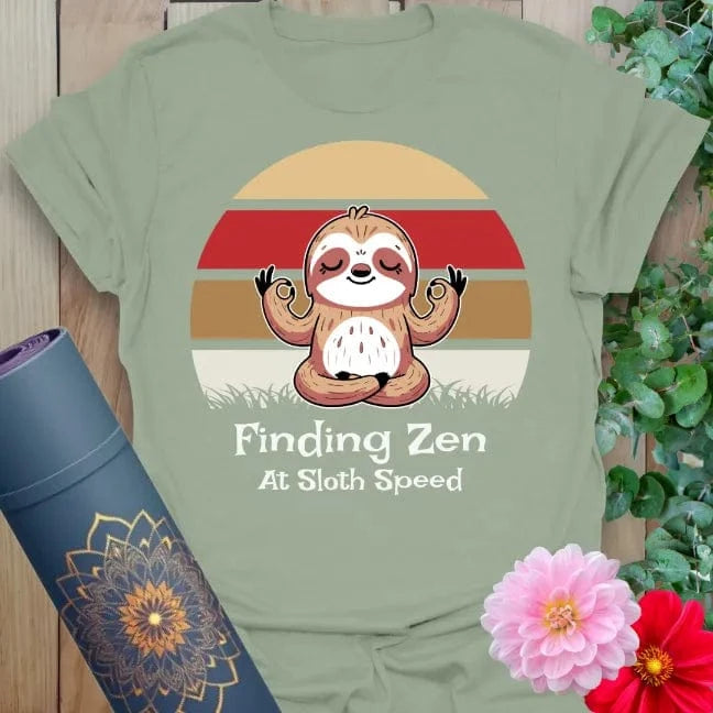 Calm sage green yoga t-shirt featuring serene sloth illustration and "Finding Zen at Sloth Speed" message for grounded, joyful mindfulness.