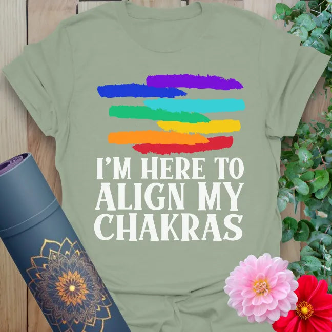 Calm sage green yoga t-shirt with rainbow brushstrokes and “Align My Chakras” text symbolizing colorful energy and grounded humor.