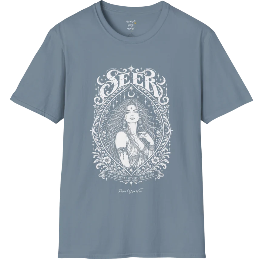 A short sleeved tee called the Seer T-Shirt, flat lay and a soft cotton shirt. Simply says, You see what others walk past. Design highlights an ornate engraved almond-shaped frame of florals and filigree around a close portrait of a long-haired figure with a star on the brow, crescent moon earrings and one hand at the collarbone, beneath a crescent moon and hanging stars, with Seer in decorative lettering across the top and the tagline on a banner below. Color is Stone Blue.