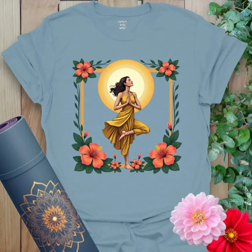 Muted stone blue yoga t-shirt with vibrant yogi, floral, and sun artwork symbolizing rootedness, growth, and inner light.