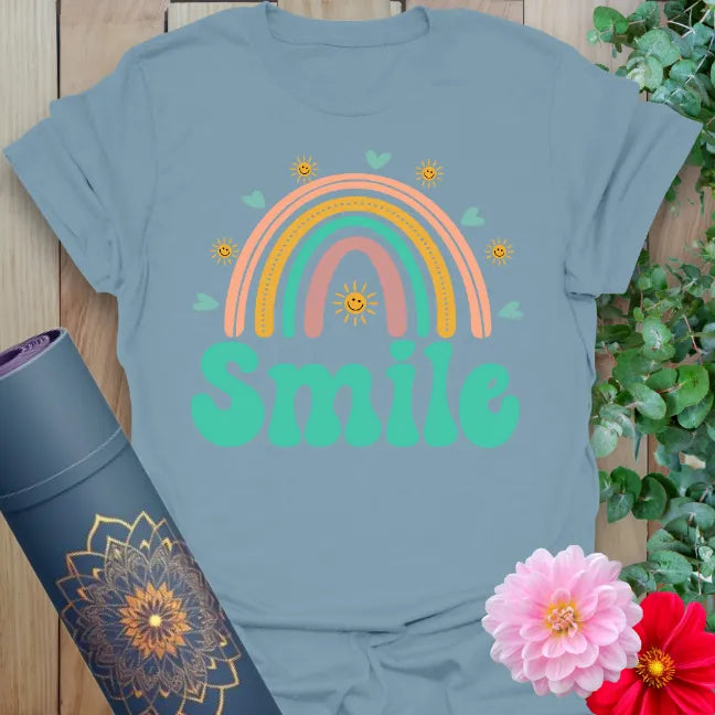 Muted stone blue yoga t-shirt with colorful rainbow and happy "Smile" artwork inspiring mindful positivity and heartfelt living.