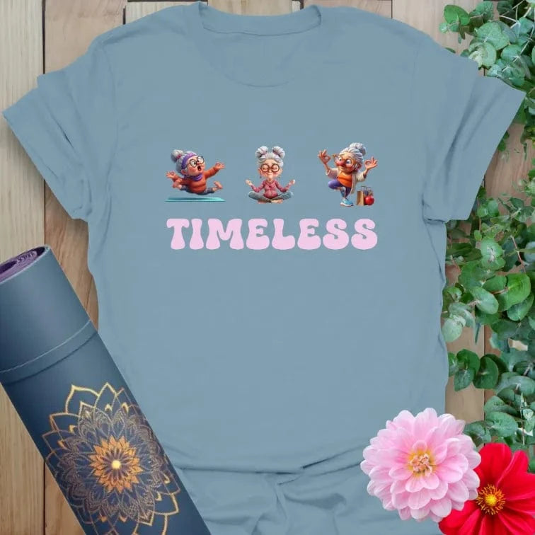 Muted stone blue t-shirt with animated elder yogi/dancer design and “TIMELESS” script for graceful, ageless living.