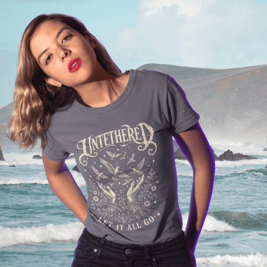 Ramro Yoga Wear Untethered tee in Dark Heather Grey — hands releasing birds wildflowers vintage design, coastal ocean lifestyle shot