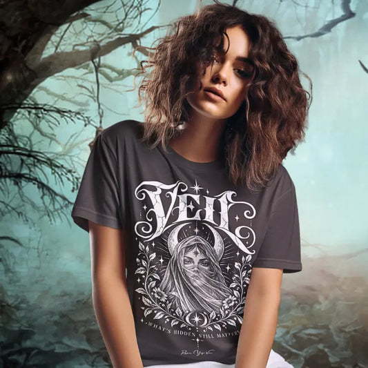 A woman stands on a misty forest path surrounded by trees, wearing the Veil T-Shirt. Veil T-Shirt is a Gildan 64000 and the color is Dark Chocolate.