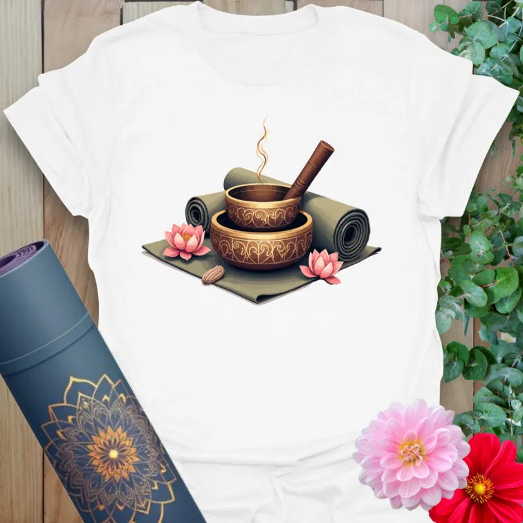 Clean white unisex yoga t-shirt featuring singing bowls, incense, and lotus flowers design inspiring mindful calm and sacred presence.