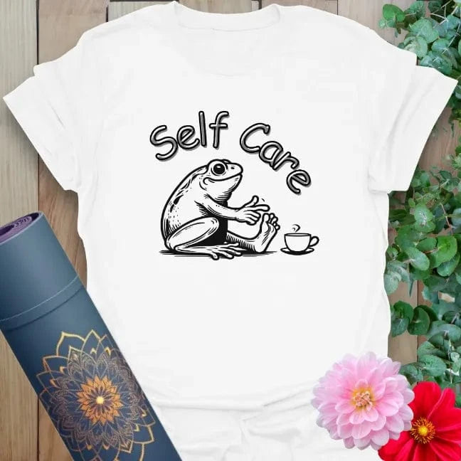 Clean white unisex yoga t-shirt featuring whimsical "Self Care" frog design for cozy, soulful relaxation and light-hearted mindfulness.