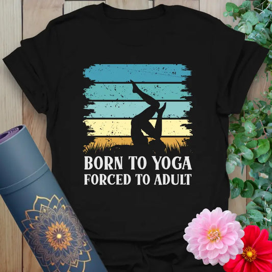 Flatlay of black Adult T-Shirt with “Born to Yoga, Forced to Adult” graphic in retro sunset colors lovingly crafted by Ramro.