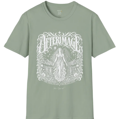 A short sleeved tee called the Afterimage T-Shirt, flat lay and a Gildan 64000 shirt on a white background. Simply says, Some Things Stay Long After The Light Leaves. Design highlights a long-haired figure in a flowing gown standing before a faint ghosted double of herself, under a starry sky with mountains, a lake and an ornate floral frame. Color is Sage.