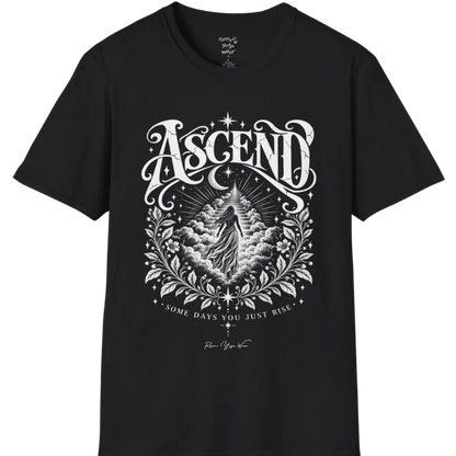 A short sleeved Tee with a figure rising through layered clouds toward a staircase of light, framed by a diamond-shaped botanical border with stars and a crescent moon above. Ascend T-Shirt flat lay is a Gildan 64000 and the color is Black.