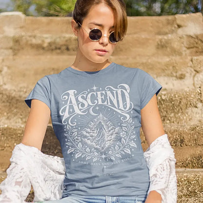 A woman in sunglasses and lace shirt poses against stone stairs, wearing the Ascend T-Shirt. Ascend T-Shirt is a Gildan 64000 and the color is Stone Blue.