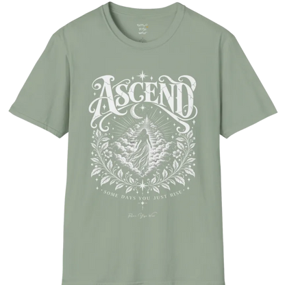 A short sleeved Tee with a figure rising through layered clouds toward a staircase of light, framed by a diamond-shaped botanical border with stars and a crescent moon above. Ascend T-Shirt flat lay is a Gildan 64000 and the color is Sage.