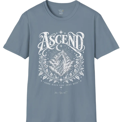 A short sleeved Tee with a figure rising through layered clouds toward a staircase of light, framed by a diamond-shaped botanical border with stars and a crescent moon above. Ascend T-Shirt flat lay is a Gildan 64000 and the color is Stone Blue.