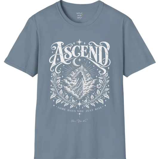 A short sleeved Tee with a figure rising through layered clouds toward a staircase of light, framed by a diamond-shaped botanical border with stars and a crescent moon above. Ascend T-Shirt flat lay is a Gildan 64000 and the color is Stone Blue.