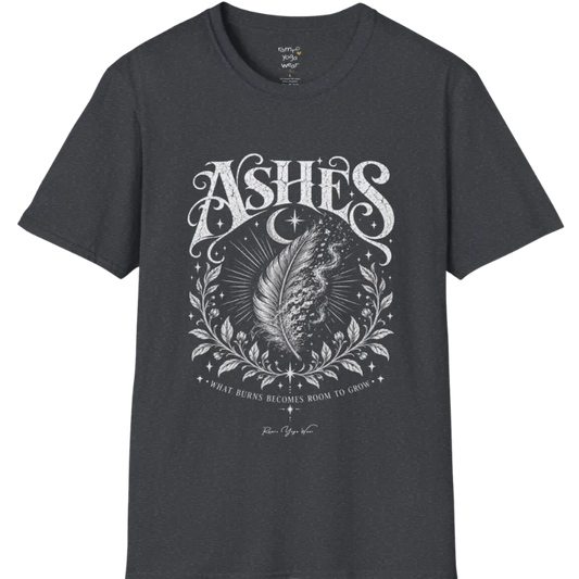 A single feather transforming into ash and ember against a dark starlit background, botanical framing below. Ashes T-Shirt flat lay is a Gildan 64000 and the color is Dark Heather Grey.