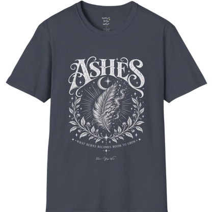 A single feather transforming into ash and ember against a dark starlit background, botanical framing below. Ashes T-Shirt flat lay is a Gildan 64000 and the color is Heather Navy.