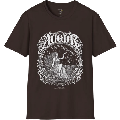 A short sleeved tee called the Augur T-Shirt, flat lay and a soft cotton shirt. Simply says, Some things tell you what's coming, if you look up. Design highlights an ornate engraved circular frame of florals and filigree around a long-haired figure in a flowing gown seated on a rocky ledge, one hand raised toward a flock of birds crossing a starry sky, with crescent moons, mountains and still water behind and Augur in decorative lettering across the top. Color is Dark Chocolate.