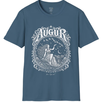A short sleeved tee called the Augur T-Shirt, flat lay and a soft cotton shirt. Simply says, Some things tell you what's coming, if you look up. Design highlights an ornate engraved circular frame of florals and filigree around a long-haired figure in a flowing gown seated on a rocky ledge, one hand raised toward a flock of birds crossing a starry sky, with crescent moons, mountains and still water behind and Augur in decorative lettering across the top. Color is Indigo Blue.