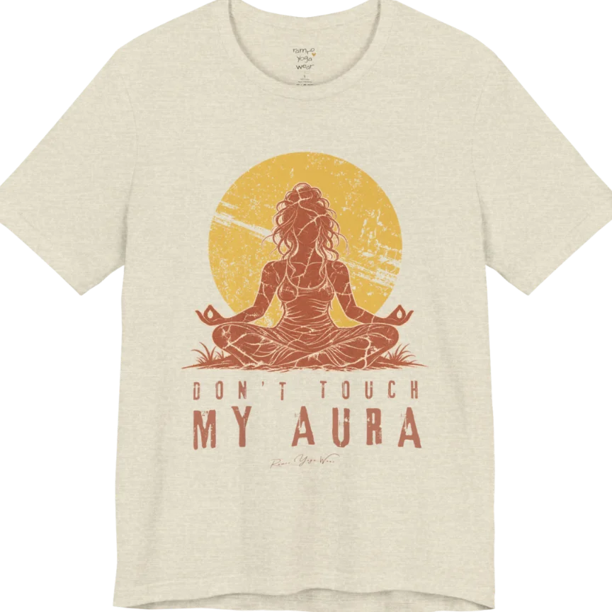 A short sleeved teed called the Aura T-Shirt, flat lay and a Bella + Canvas 3001 shirt. Simply says, Don't Touch My Aura. Design highlights a person meditating with a large bright sun in the background, all in a rustic, distressed illustration. Color is Heather Prism Natural.